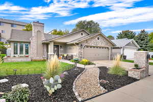 View of front facade featuring a fenced front yard, stucco siding, concrete driveway, a chimney, and a garage