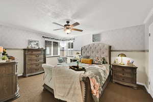 Bedroom featuring wallpapered walls, ceiling fan, and a textured ceiling