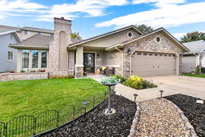 View of front of house featuring a chimney, concrete driveway, a garage, stucco siding, and stone siding