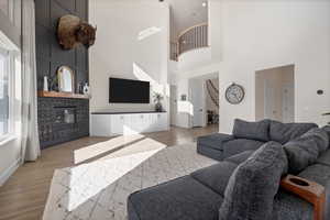 Living area featuring a tile fireplace, light wood-style floors, a high ceiling, and stairway