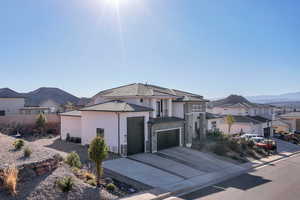 French country home with stone siding, a residential view, driveway, stucco siding, and a garage