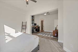 Carpeted bedroom with an office area and ceiling fan