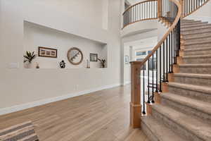 Stairs with wood finished floors and a high ceiling