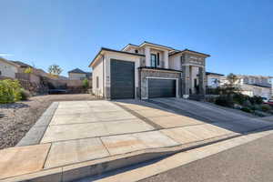 Modern home featuring a trampoline, stucco siding, stone siding, and driveway
