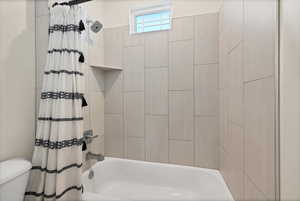 Bathroom featuring shower / bath combination with curtain and toilet