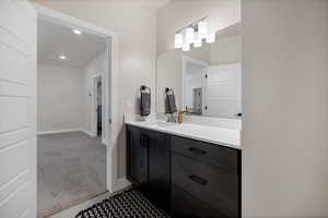 Bathroom featuring light colored carpet, vanity, and recessed lighting
