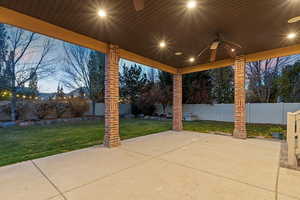 Patio terrace at dusk with ceiling fan, a patio area, and a fenced backyard