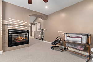Workout area with lofted ceiling, light carpet, a tiled fireplace, recessed lighting, and a ceiling fan