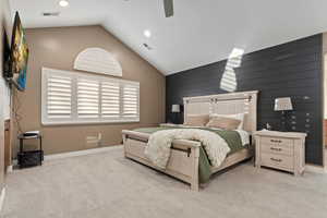Bedroom with light colored carpet, a ceiling fan, wooden walls, high vaulted ceiling, and recessed lighting