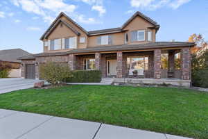 View of front of home with covered porch, brick siding, stucco siding, and a garage