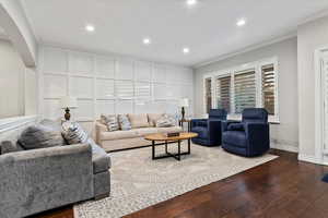 Living room featuring crown molding, recessed lighting, wood-type flooring, and arched walkways