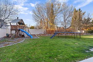 Fenced backyard featuring a playground and a trampoline