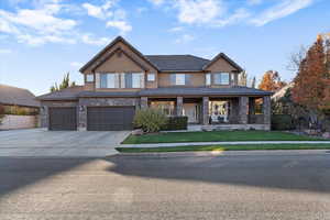 View of front of home featuring covered porch, concrete driveway, stucco siding, a garage, and brick siding