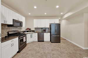 Kitchen featuring dark countertops, appliances with stainless steel finishes, white cabinetry, recessed lighting, and decorative backsplash