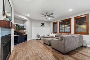 Living room with a fireplace, wood finished floors, a ceiling fan, and recessed lighting