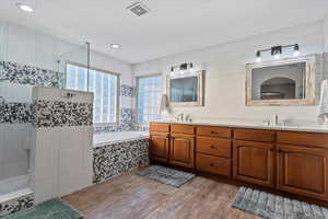 Bathroom featuring a walk in shower, double vanity, light wood-type flooring, a garden tub, and recessed lighting