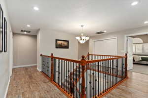 Hall featuring a chandelier, recessed lighting, an upstairs landing, and light wood-style flooring