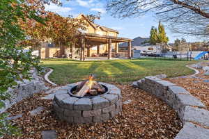View of yard featuring a trampoline, a patio area, and a fire pit