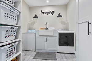 Laundry area with independent washer and dryer, cabinet space, and light wood finished floors