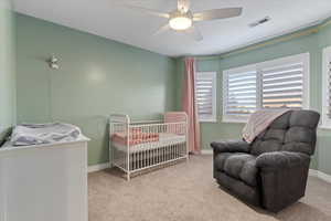 Carpeted bedroom with a crib and a ceiling fan
