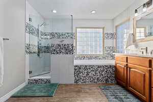 Bathroom featuring a bath, vanity, light wood-style floors, healthy amount of natural light, and recessed lighting