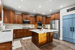 Kitchen featuring stainless steel appliances, light stone countertops, a kitchen island, dark wood-style floors, and recessed lighting