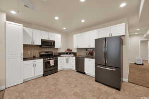 Kitchen with stainless steel appliances, dark countertops, white cabinetry, decorative backsplash, and recessed lighting