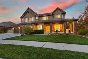 View of front of property with covered porch, stucco siding, a front lawn, concrete driveway, and brick siding