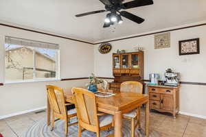 Dining room with light tile patterned flooring, crown molding, and a ceiling fan