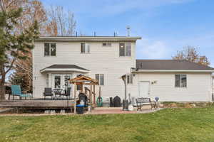 Back of house featuring a lawn, a patio area, and a shingled roof