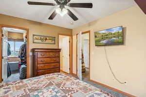 Bedroom featuring light carpet, a ceiling fan, and a walk in closet