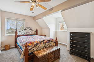 Carpeted bedroom featuring ceiling fan and vaulted ceiling