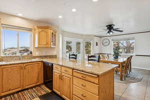 Kitchen featuring light stone countertops, a peninsula, dishwasher, recessed lighting, and glass insert cabinets