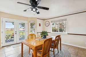 Dining area with light tile patterned floors, french doors, ornamental molding, and ceiling fan