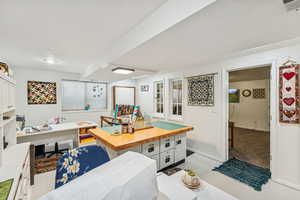 Kitchen featuring white cabinets, butcher block counters, a desk, and a center island