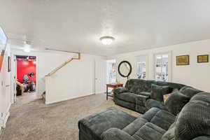 Carpeted living room featuring stairs and a textured ceiling