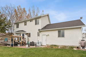 Back of house featuring a gazebo, roof with shingles, a yard, and a patio