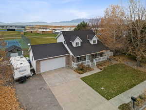 View of front of property featuring covered porch, a front lawn, driveway, a mountain view, and brick siding