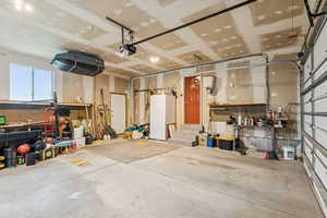 Garage featuring freestanding refrigerator and a garage door opener