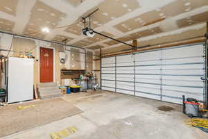 Garage with a garage door opener and freestanding refrigerator
