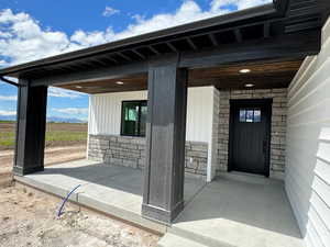 Doorway to property featuring stone siding and covered porch