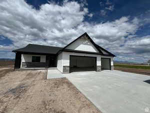Modern farmhouse featuring stone siding, driveway, and a garage