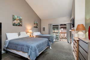 Carpeted bedroom with high vaulted ceiling and a wall mounted air conditioner