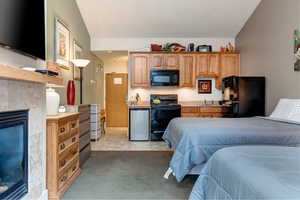 Bedroom featuring a tile fireplace, freestanding refrigerator, light carpet, and light tile patterned floors