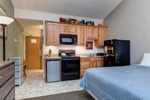 Kitchen with black appliances, light countertops, and light tile patterned floors
