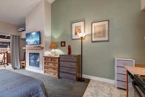Bedroom with light carpet and a tile fireplace