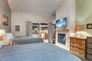 Carpeted bedroom with access to exterior, a tiled fireplace, and a wall mounted air conditioner