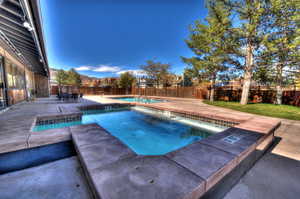 View of swimming pool featuring a patio area, a community hot tub, and a fenced backyard