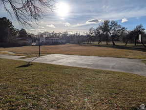 View of green lawn featuring community basketball court and view of scattered trees