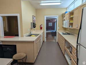Kitchen featuring light countertops, white appliances, light brown cabinets, and a peninsula